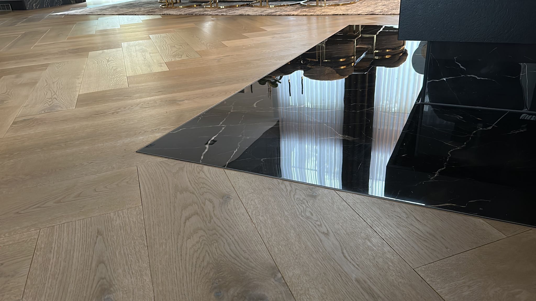 Detailaufnahme einer Marmorfliese, eingelassen in hochwertiges Laminat, vor dem neu gestalteten Kamin.