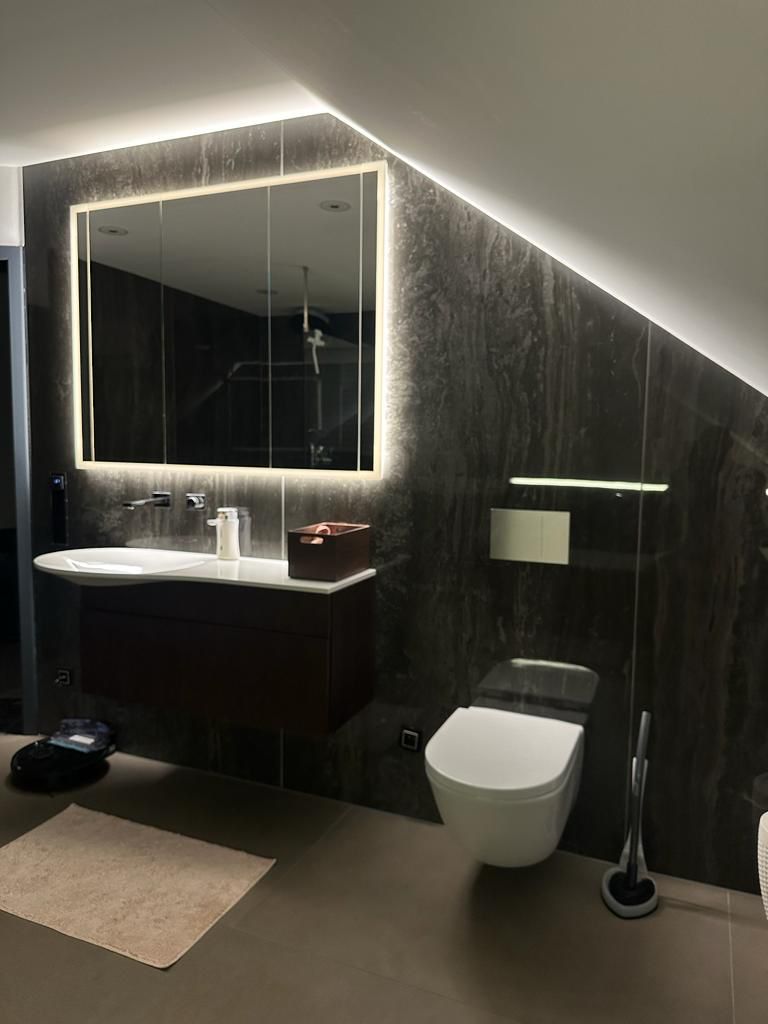 Neu gestaltetes Badezimmer, mit indirekter Ambientebeleuchtung des Spiegels über dem Waschbecken. 